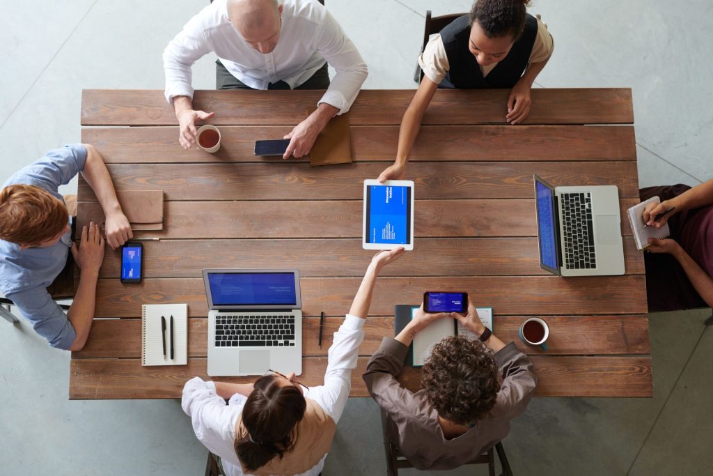 A diverse group of professionals engaged in a productive office meeting using digital devices.